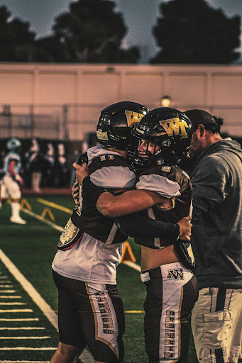 Varsity outside linebacker and running back Reave Comer (12) hugs Varsity outside linebacker Tyler Schlappatha (11) before the start of the game. “There was a lot of emotion in the air,” Comer commented.