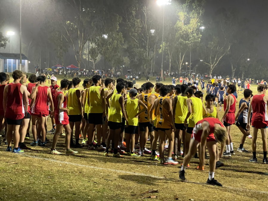 The West High JV and Varsity Cross Country teams file into their place at the starting line, anxiously awaiting the starting gun. Raindrops, visible in the rays of the floodlights, hit the faces of the boys — mixing with beading sweat in the heat. 