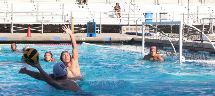 Joseluis Ayala (12) reaches for a shot block against the Torrance Tartars, while De La Torre focuses on the play, prepared to save.