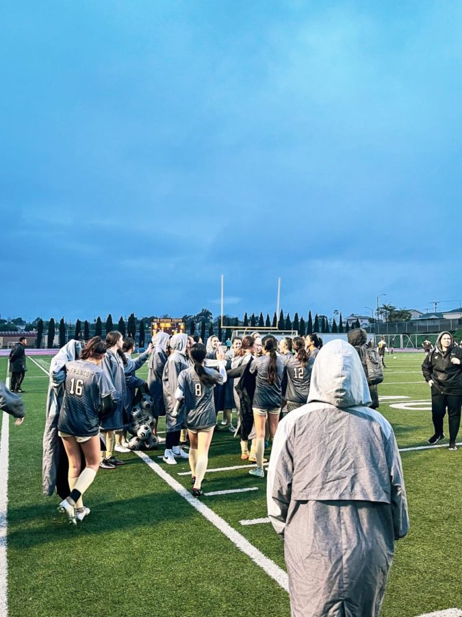 The Girls’ Varsity Soccer team goes in for a final group huddle in the rain after the game is finished. The team and the coach discussed the game and other matters regarding the next game. 