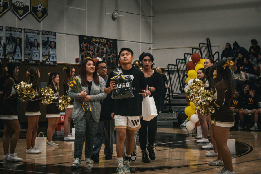 Kyle Cajigal (12) walks on court with his family for the Basketball Senior Night ceremony. 
