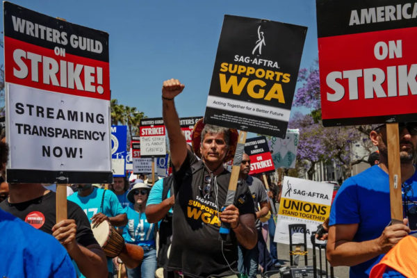 Members of the SAG-AFTRA march to support the WGA on strike. Many workers can be seen walking together in peaceful protest. Some of the subjects of conflict are portrayed on the signs waved by the marching protesters.
Photo courtesy of Los Angeles Times
