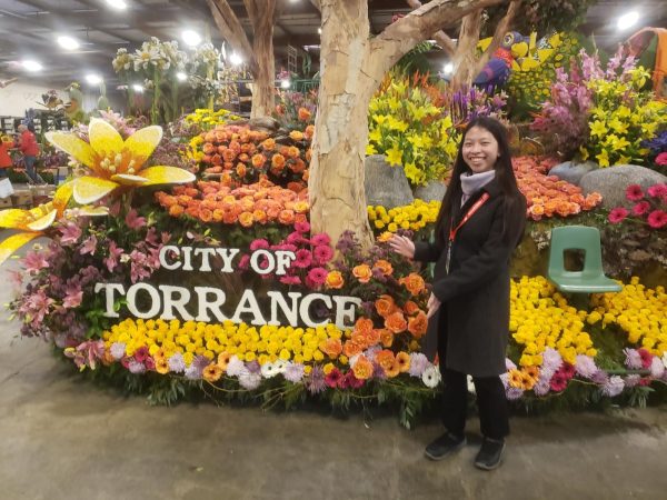 Cheng beckons proudly towards Torrances 2024 Rose Parade float, The Lyrical Call of Nature. Submitted for a school art assignment, her design beat out 16 other high school contestants in a citywide competition to represent Torrance in the 2024 Tournament of Roses on New Years Day. Photo courtesy of Jodie Cheng (12).