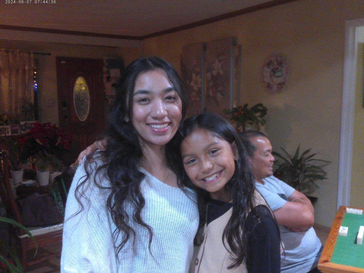 During a cozy thanksgiving gathering, two cousins paused for a quick photo in the living room. The living room is filled with family and laughter fills the space. In the background, grandparents, uncles, and aunts gathered around the mahjong table keeping a long family tradition alive. Surrounded by warm lights, plants, and holiday decor. The moment captures the joy of thanksgiving and portrays the closeness charred through the evening. 
